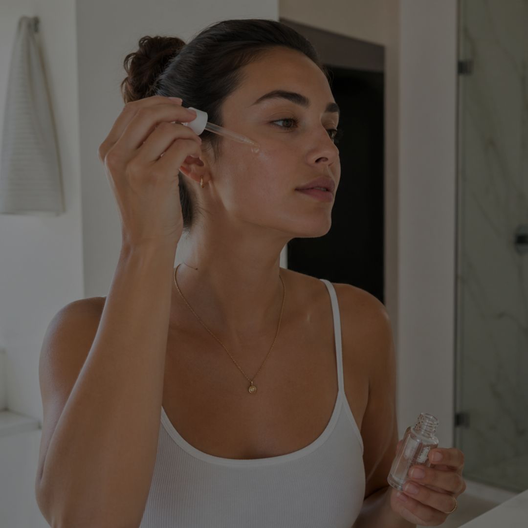 Woman applying a skincare product to her face in a bathroom setting