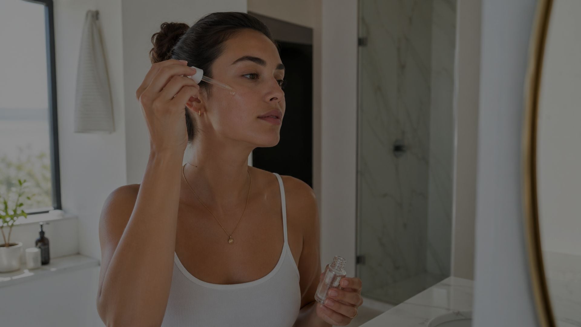 Woman applying skincare product in a bathroom setting